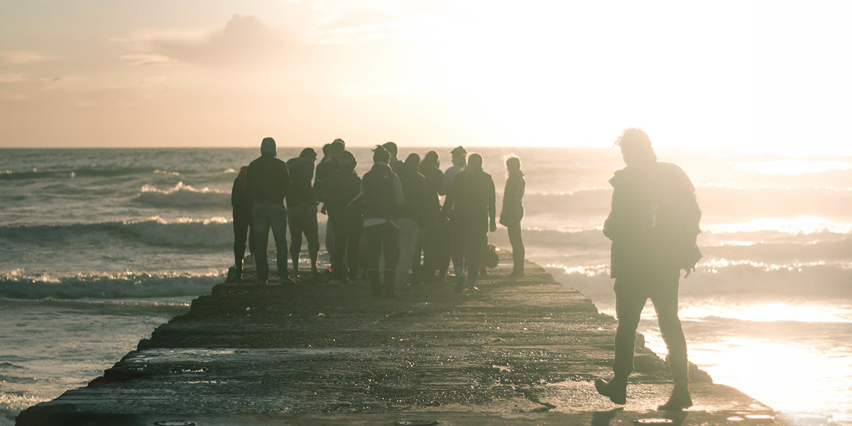 Person walking up to group standing at end of dock at twilight
