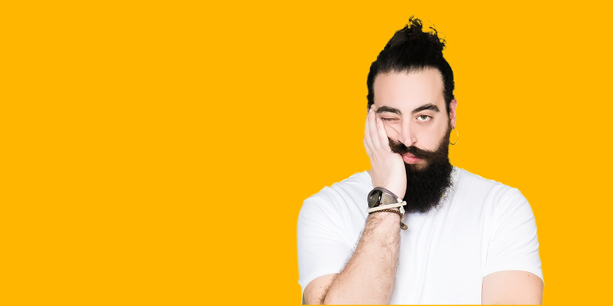 man with uninterested look holding his head up with hand on orange background