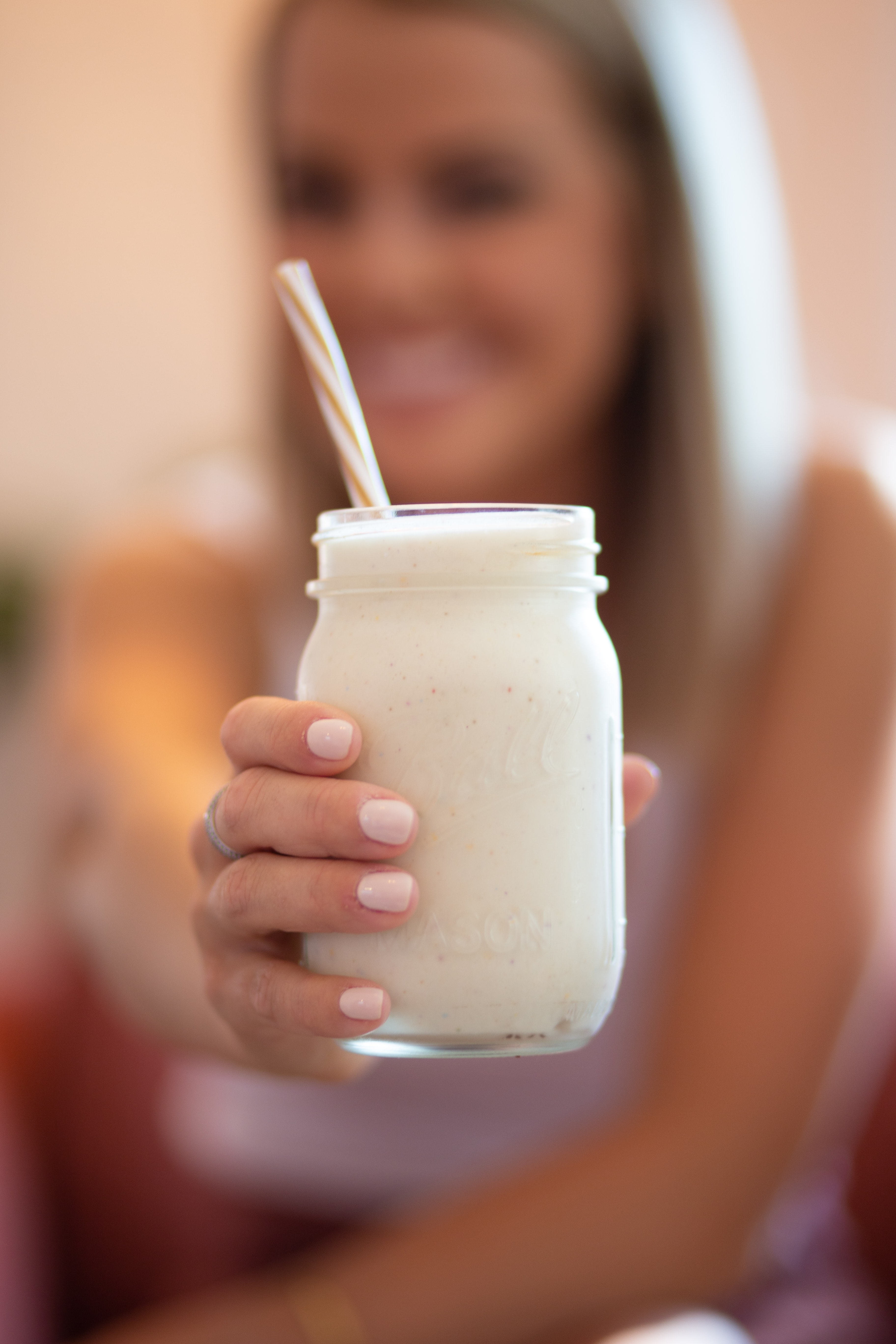Young woman holding up a mason jar filled with pumpkin smoothie