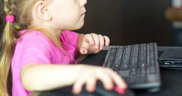 Young girl uses mouse and keyboard, stares at PC