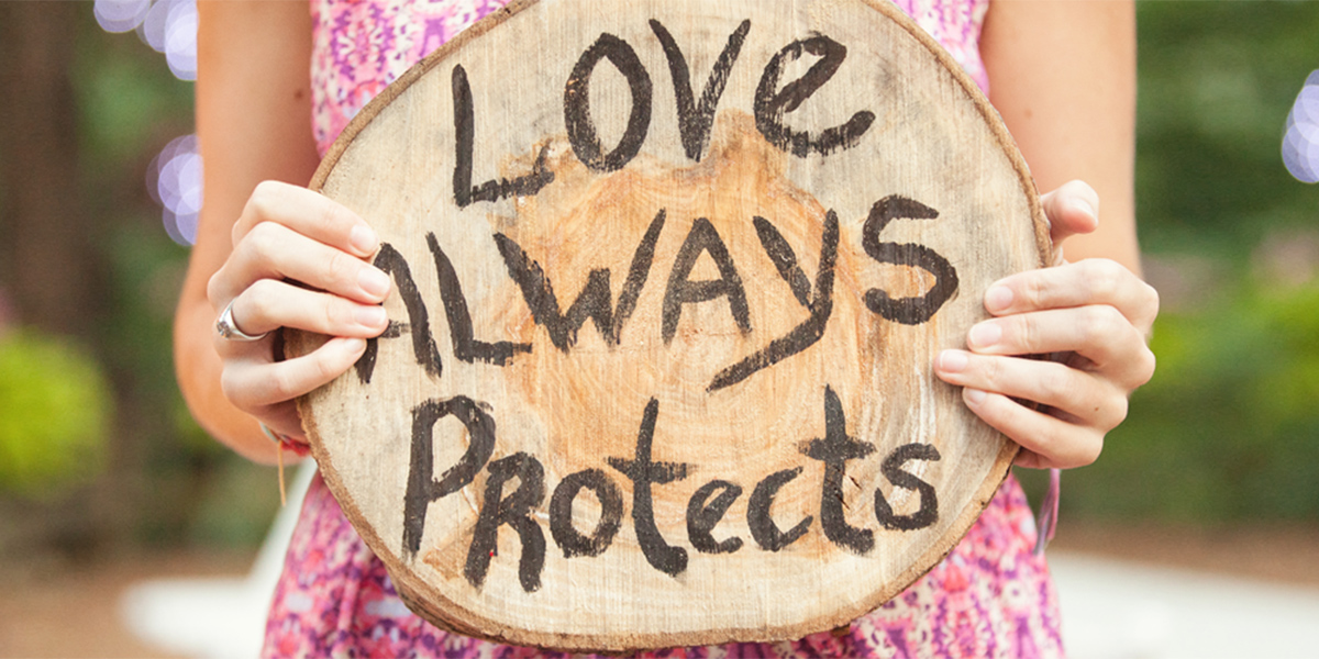 Love always protects sign hold by lady