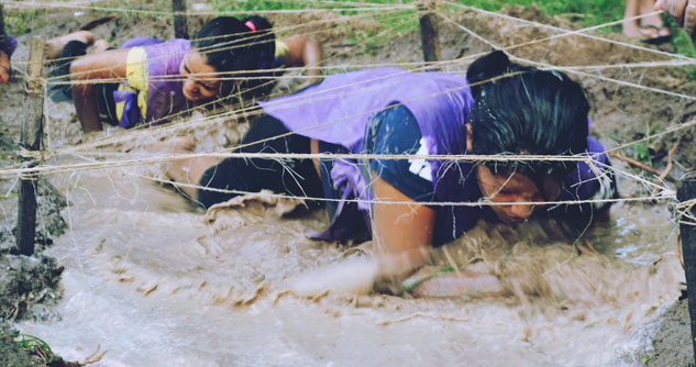 Two women crawling in mud for the Tough Mudder