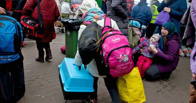 Crowds of refugees carry suitcases and backpacks