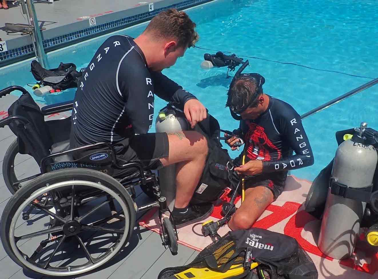 Man in wheel chair and amputee prepare for scuba lessons at swimming pool