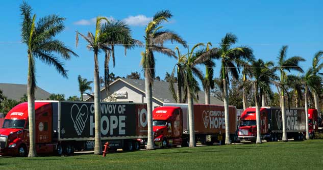 Row of Convoy of Hope trucks parked under palm trees