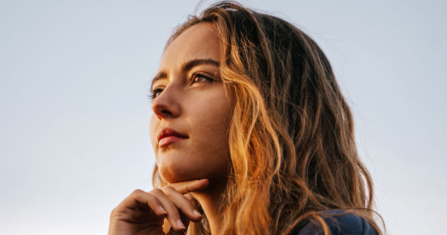 girl-stares-to-distance with finger bent under her chin