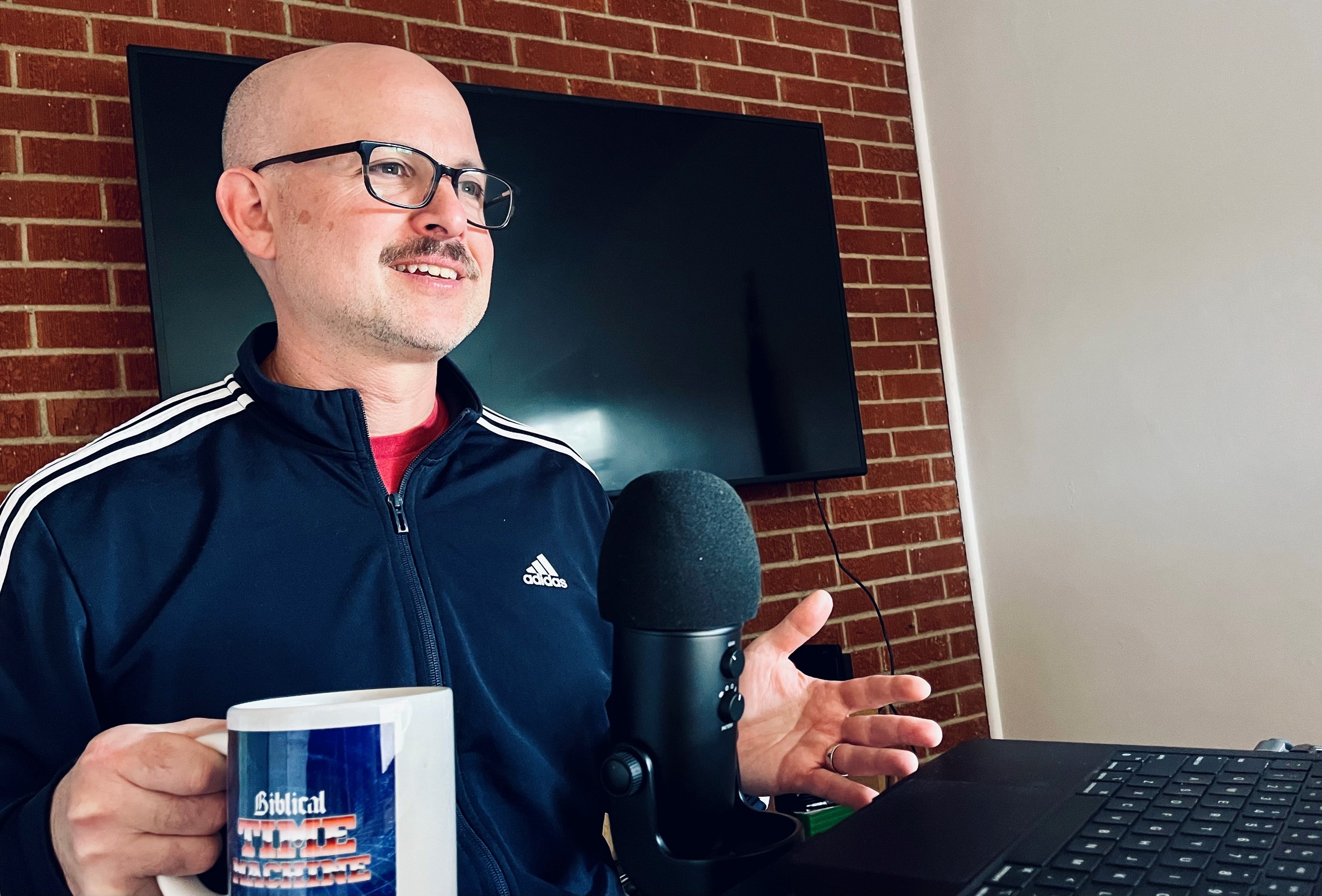 Dave Roos podcasting at mic, holding a mug