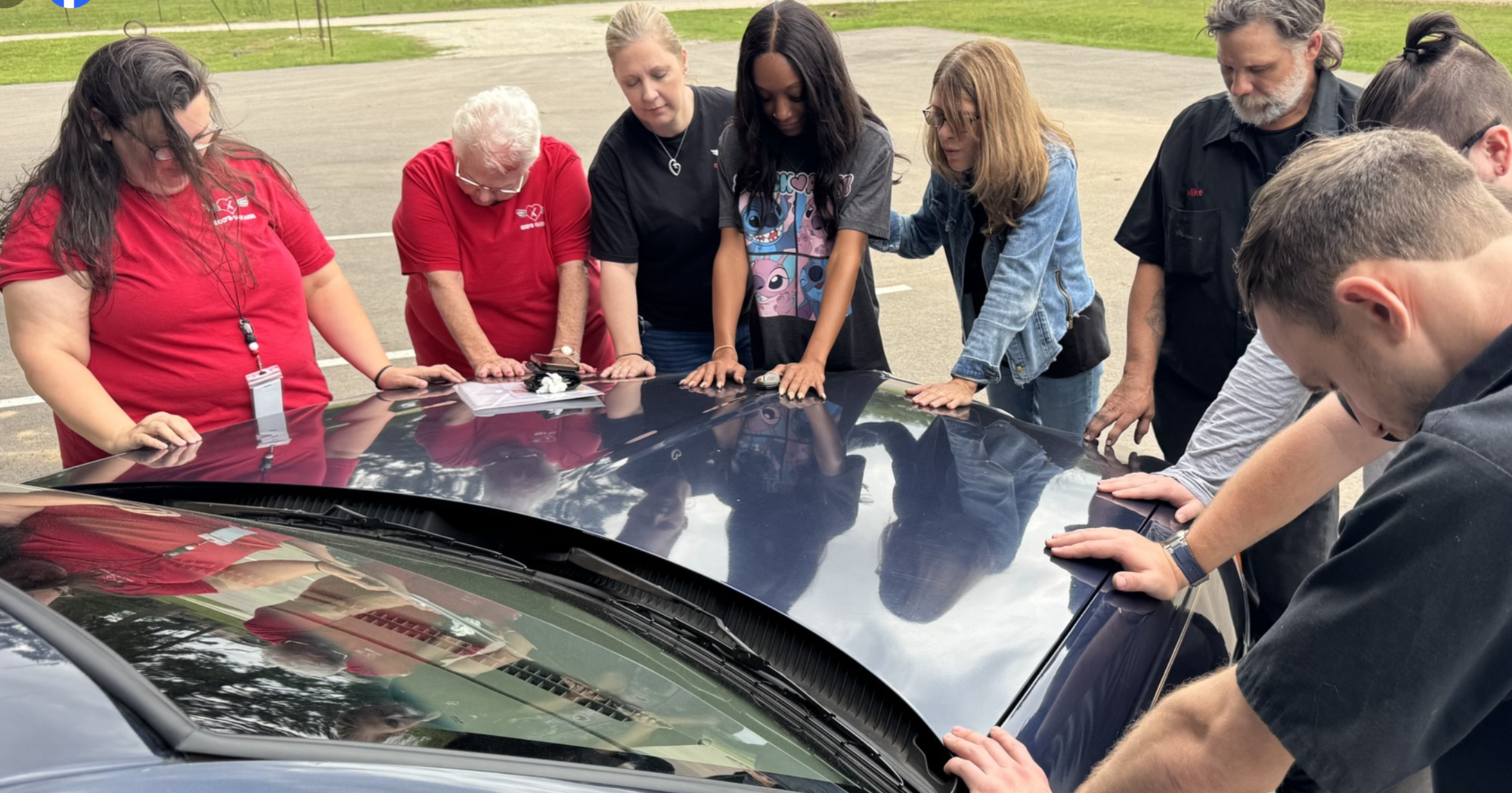 Volunteers and car recipient, praying