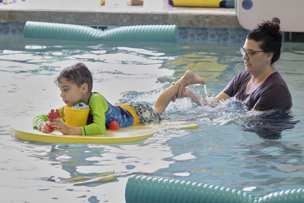Occupational therapist Angelina Price, from The Learning Center, guides a student in the water during an autism-specific swim class at Small Fish Big Fish