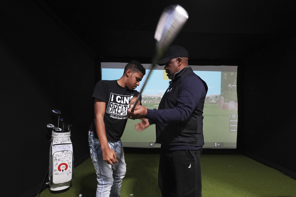 Jacento White, 16, a junior at Renaissance High School works on his swing with golf coach Jess Hawkins in Detroit