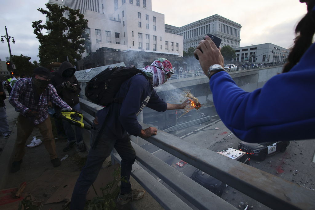 Protesters throw objects at police vehicles on a Freeway near the Metropolitan Detention Center in downtown Los Angeles
