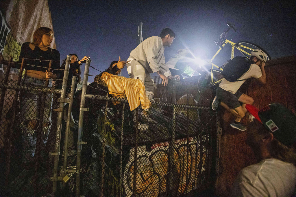 Protesters jump over a fence to avoid being kettled by police during protests 