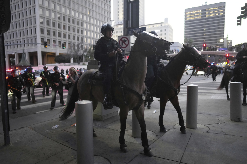 Los Angeles Police Department officers on horseback move through a street during a protest