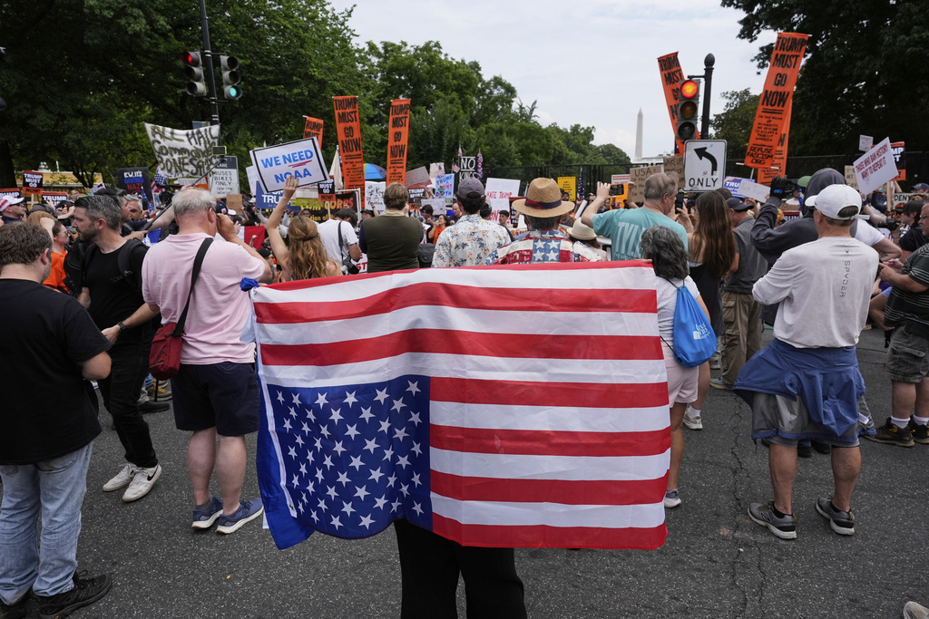A demonstrator carries an American flag upside-down near the White House during a protest taking place on the day of a military parade commemorating the Army