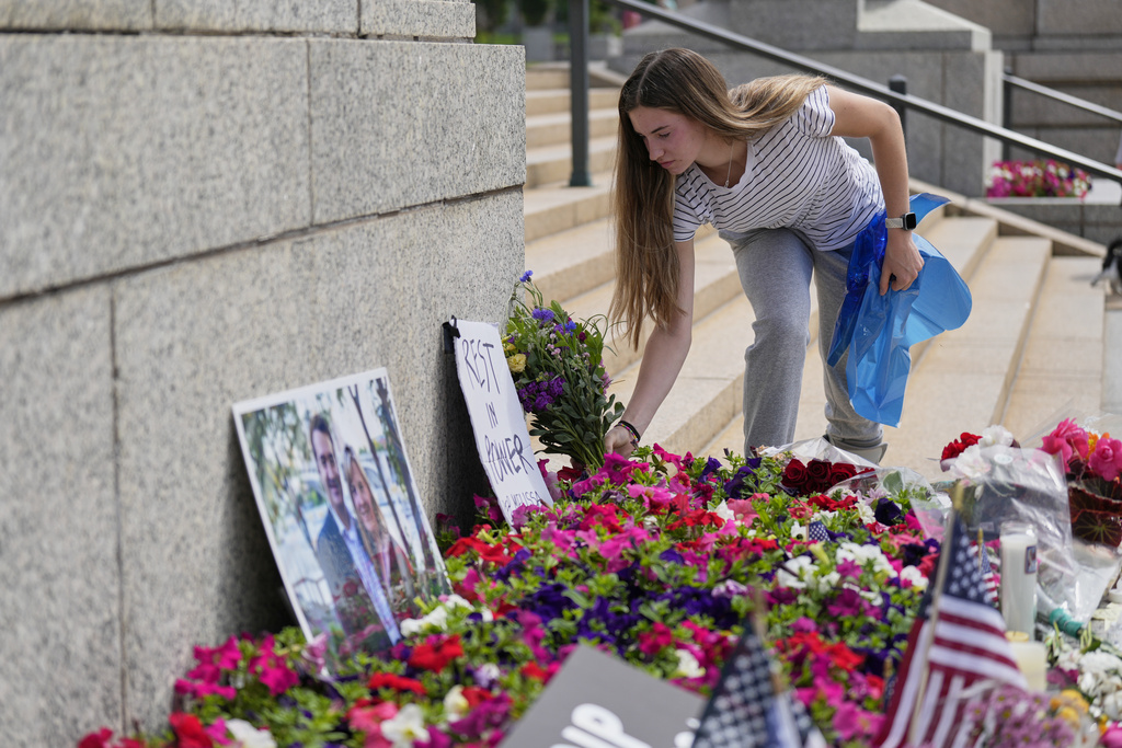Claire Stein places flowers at a makeshift memorial for Minnesota state Rep. Melissa Hortman and her husband Mark at the state Capitol