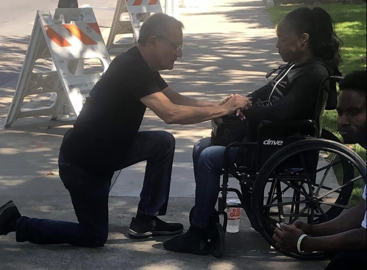 Man prays over a woman in wheelchair