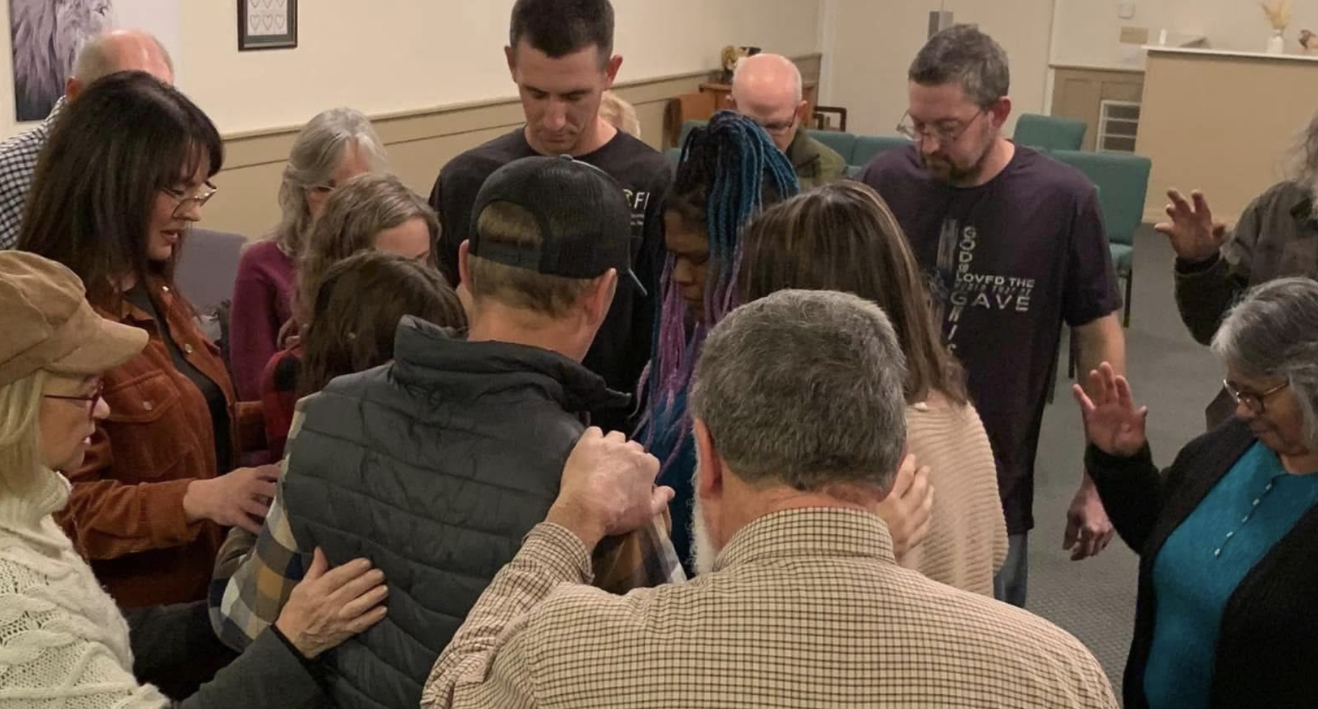 Woman surrounded by people as woman in the center prays