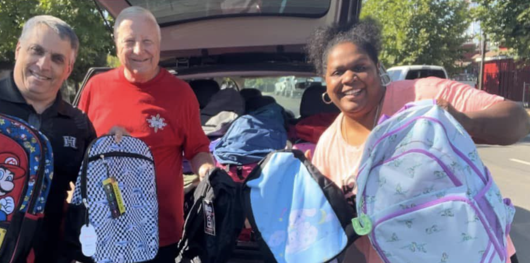 Woman and two men are giving away backpacks