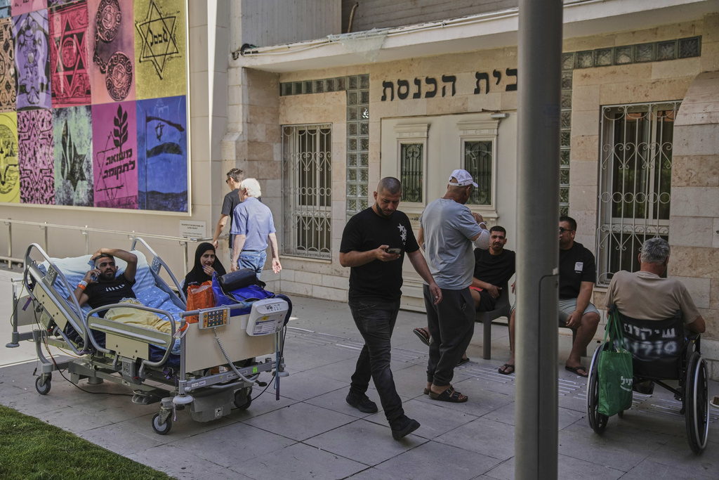 Patients rest outdoors after a building of the Soroka hospital complex was hit by a missile fired from Iran in Beersheba, Israel
