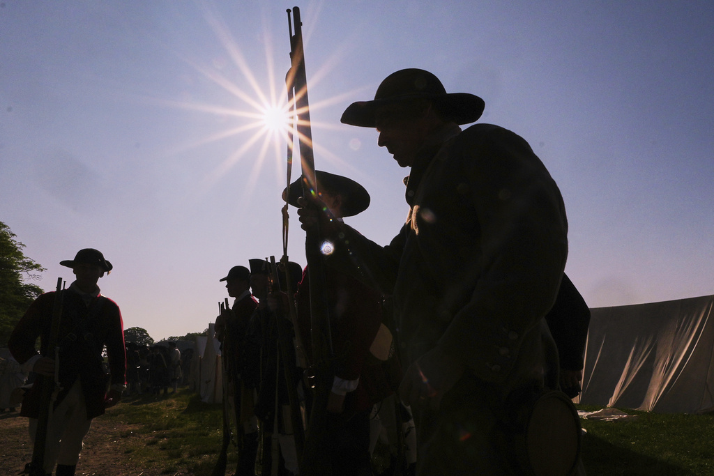 Colonial soldiers prepare to face the British during a reenactment in celebration of the 250th anniversary of the Battle of Bunker Hill
