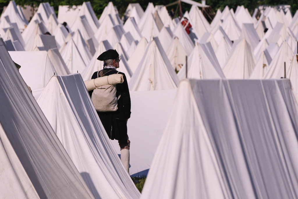 Ed Knight, of Manchester, Vt., who portrays a Colonial soldier, stands among the encampment tents during a reenactment in celebration of the 250th anniversary of the Battle of Bunker Hill