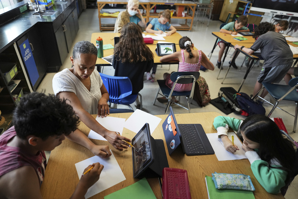 Art teacher Lindsay Johnson, second from left, teaches students how to ask Canva for help during a summer class at Roosevelt Middle School in River Forest, Ill.
