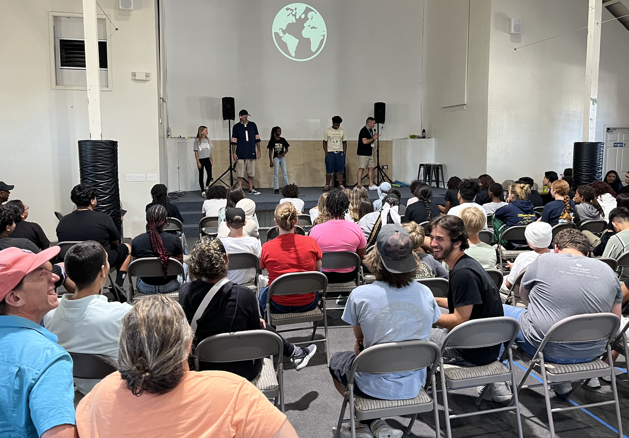 Kids on stage, young people in audience on folding chairs