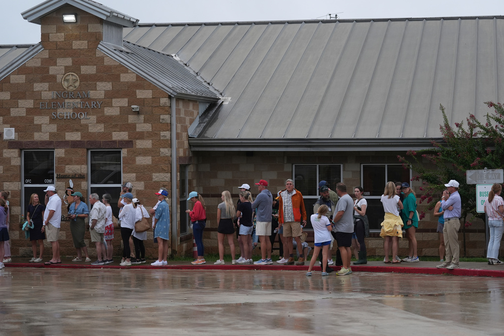 Families line up at a reunification center after flash flooding it the area in Ingram, Texas