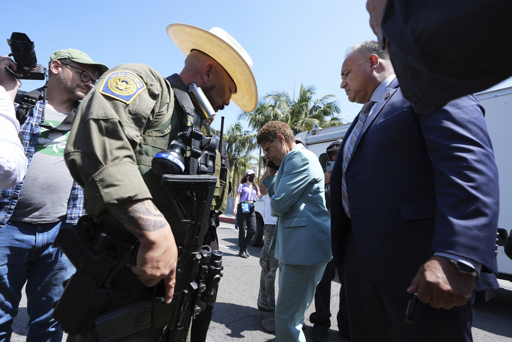 Los Angeles Mayor Karen Bass talks on her mobile phone next to a border patrol federal agent at MacArthur Park