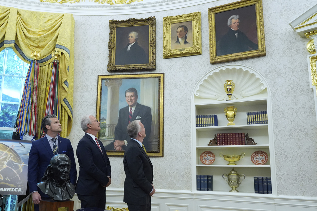 From left, Defense Secretary Pete Hegseth, Sen. Kevin Cramer, R-N.D., and Sen. Dan Sullivan, R-Alaska, look at portraits of former presidents as President Donald Trump speaks in the Oval Office