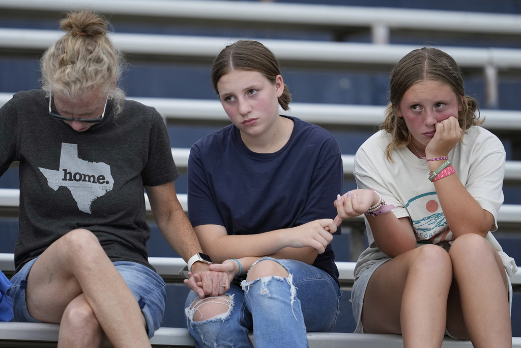 Residents hold hands during a vigil for flooding victims