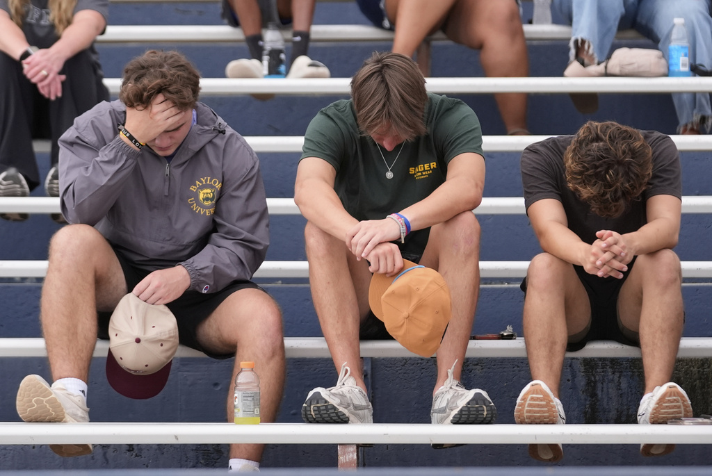Young people pray hard during a vigil for flooding victims at Tivy Antler Stadium in Kerrville, Texas