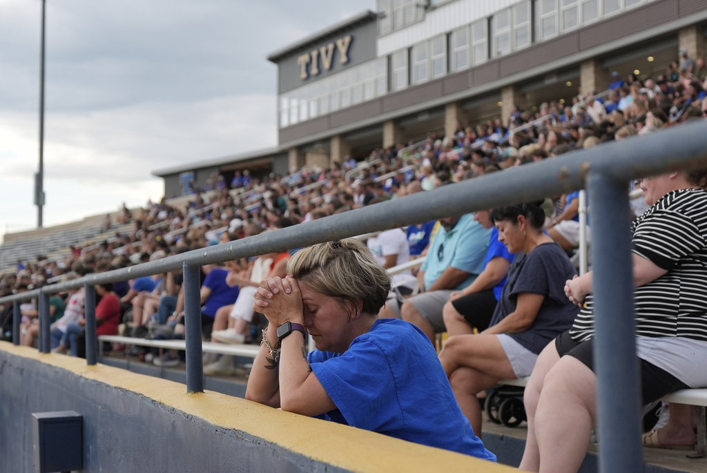 A woman prays during a vigil for flooding victims at Tivy Antler Stadium in Kerrville, Texas
