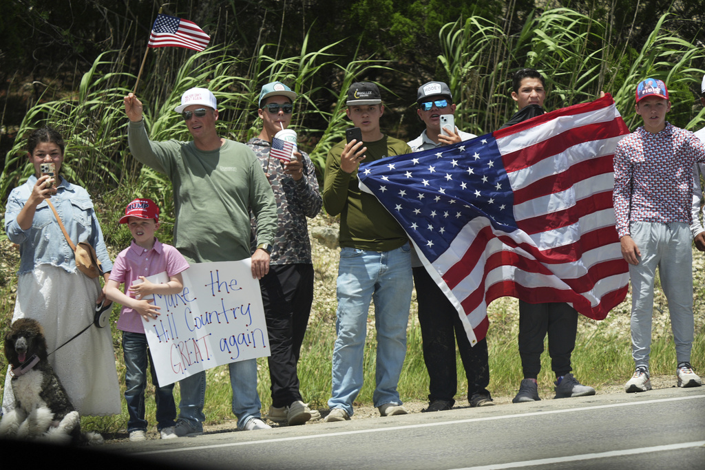 People watch as President Donald Trump and first lady Melania Trump pass in a motorcade in Kerrville, Texas