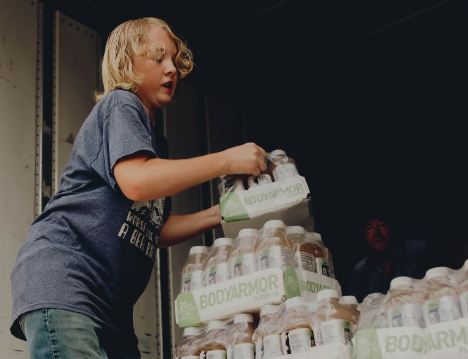 Young man unloading bottles of Body Armor from a truck