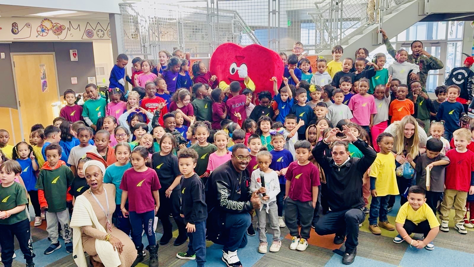 Volunteers and students pose with the Struggle of Love Foundation’s heart mascot after a community event in Denver.