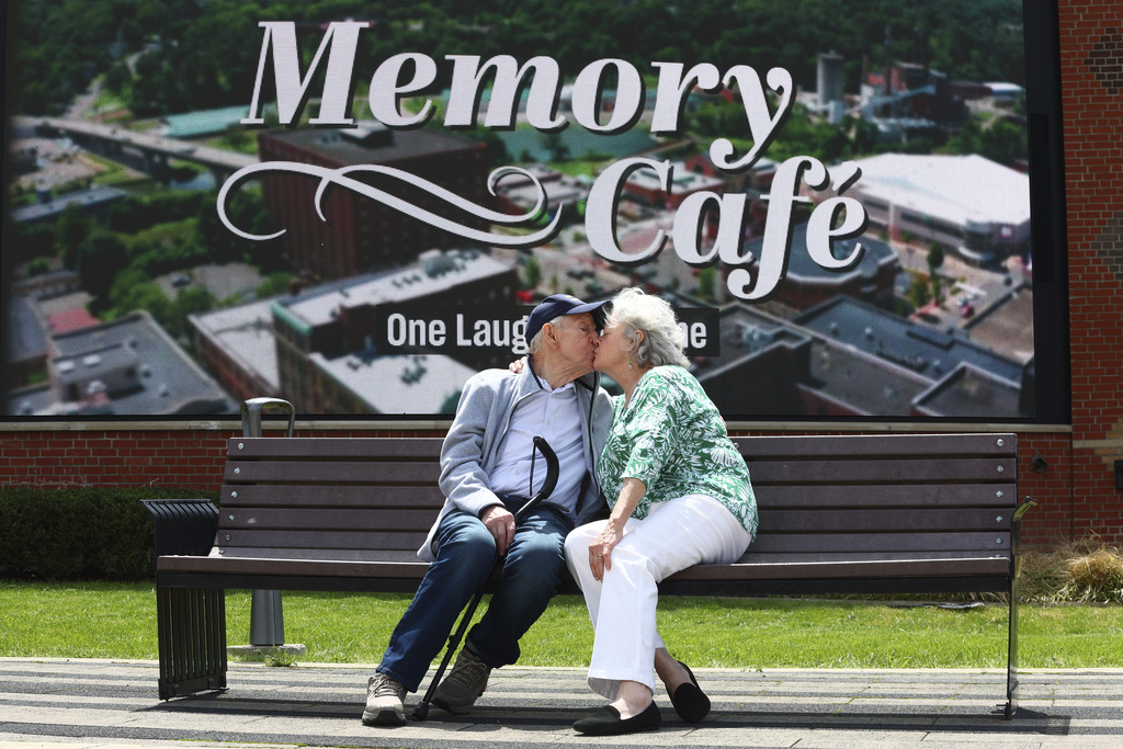 Mario and Gail Cirasunda, of Orchard Park, N.Y., share a kiss on a bench following a Memory Cafe event at the National Comedy Center