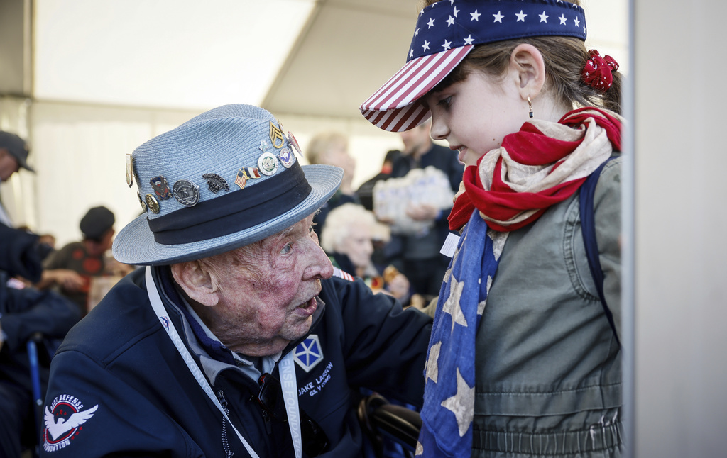 U.S. veteran SSgt. Jake M. Larson talks to a girl who wears an American flag around her neck during a gathering in preparation of the 79th D-Day anniversary in La Fiere, Normandy, France