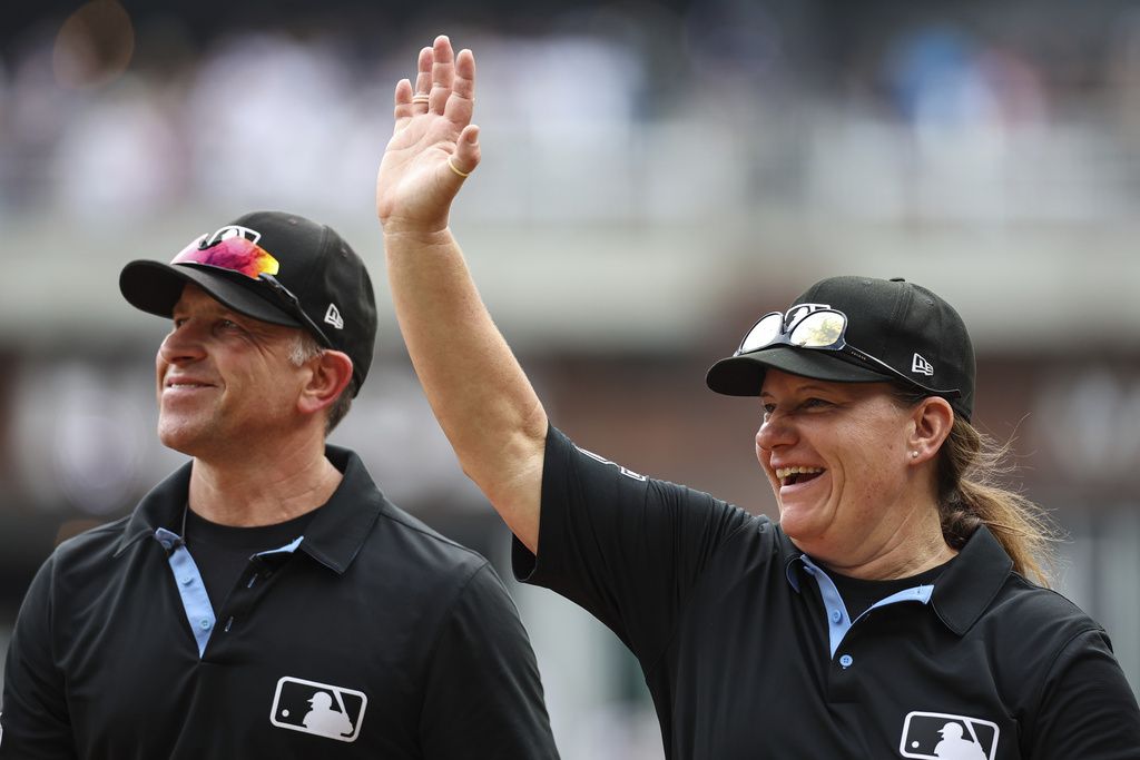 Umpires Chris Guccione, left, and Jen Pawol, right, react to fans in the crowd at the conclusion of the first baseball game of a doubleheader between the Atlanta Braves and Miami Marlins