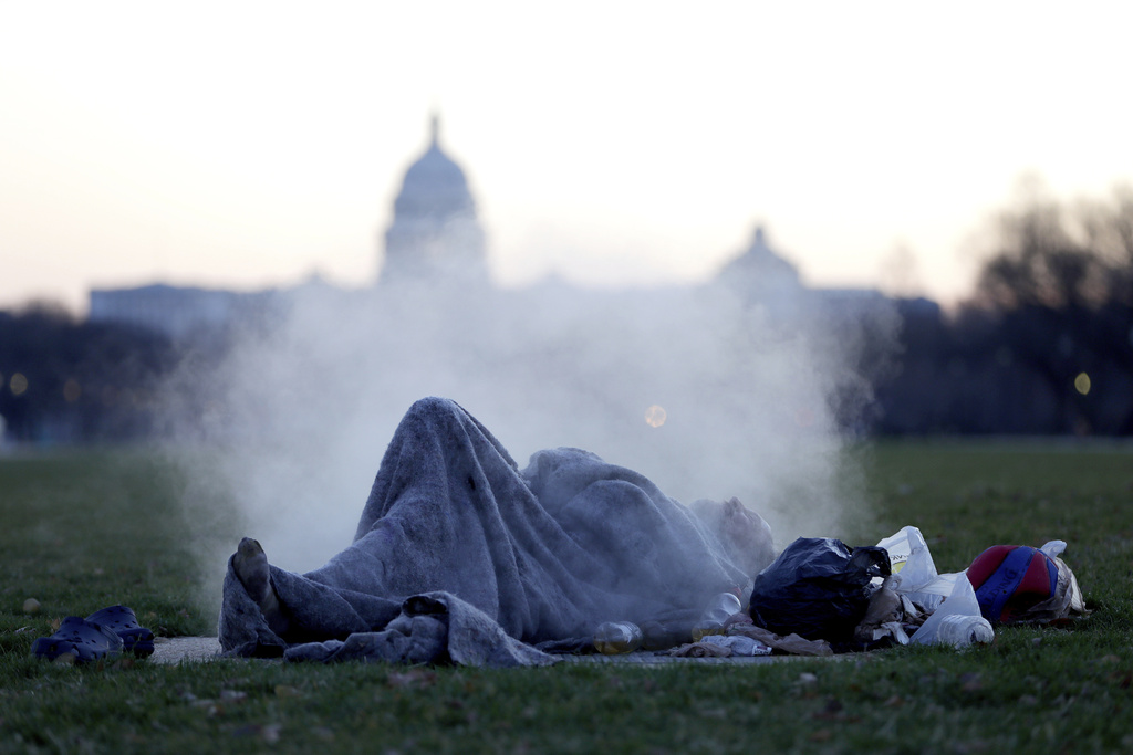 U.S. Capitol building gives backdrop to a homeless man resting on a steam vent on the National Mall