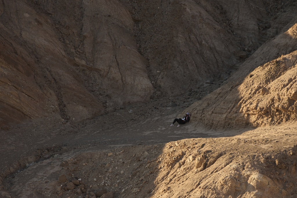 A hiker rests in the shade near Zabriskie Point in Death Valley National Park
