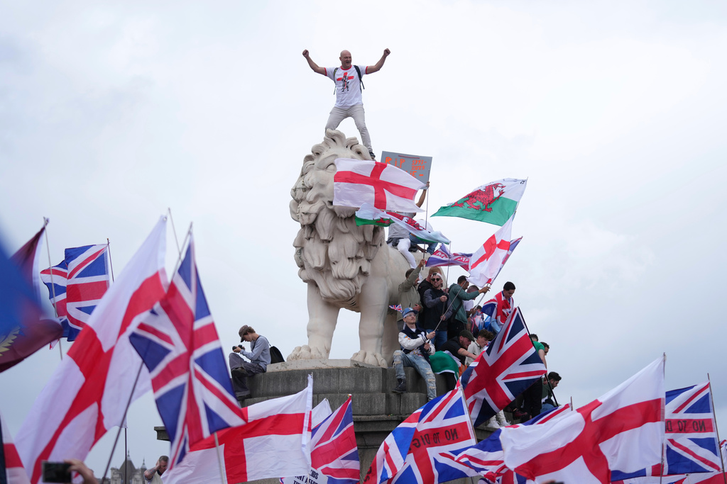 A demonstrator stands on the head of the South Bank lion that sits on the side of the Westminster Bridge