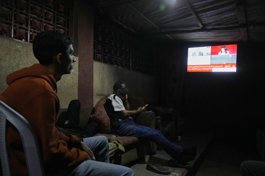 Palestinians follow the news on a television after the announcement that Israel and Hamas have agreed to the first phase of a peace plan to pause fighting