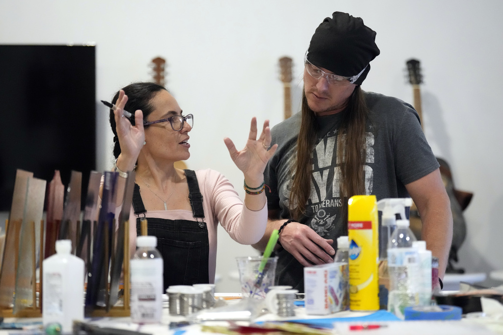 Glass artist Martha Morales Purucker, left, helps Marine veteran Chase Huddleson as he works on a piece of stained glass in the CreatiVets headquarter in Nashville, Tenn. 