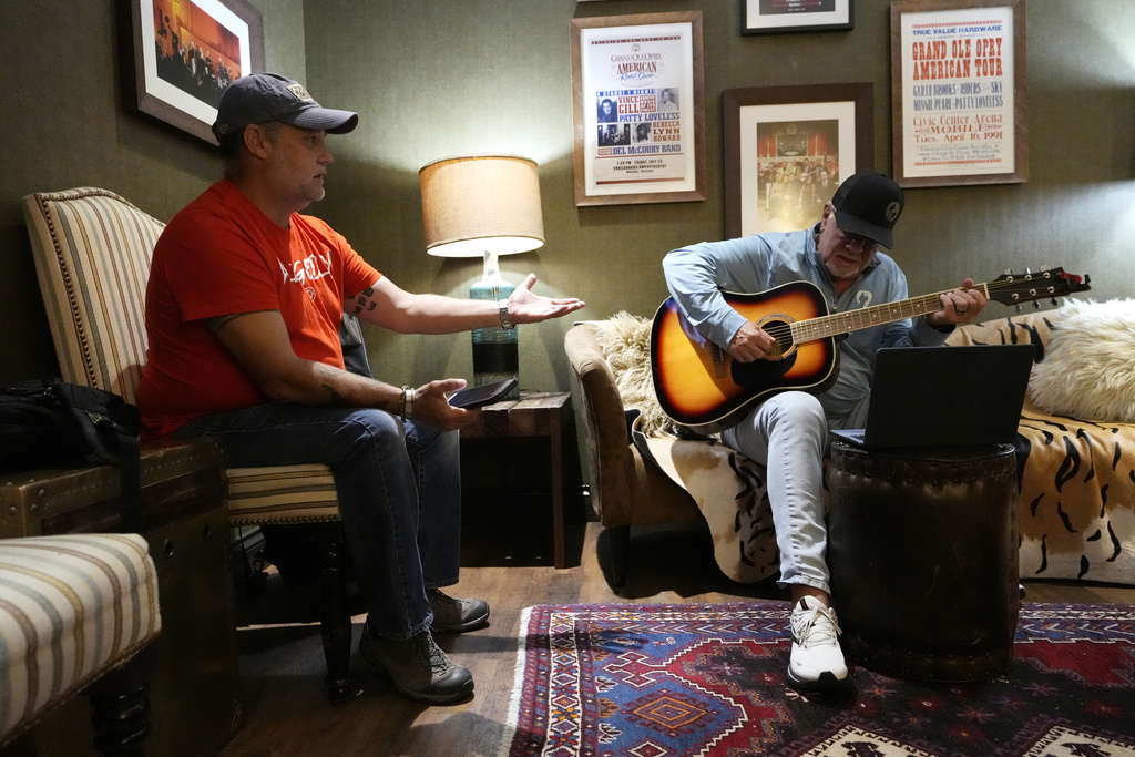Army veteran Clay Jensen, left, talks about events in his military career as songwriter Brian White, right, puts them into lyrics as they work in a dressing room in the Grand Ole Opry House 