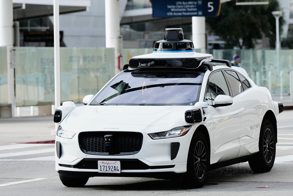 A passenger inside a Waymo vehicle looks out of the window while leaving the San Jose Mineta International Airport