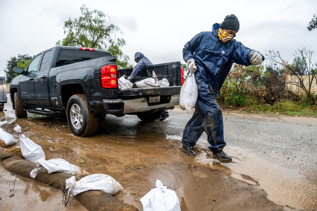 James Jones places a sandbag to prevent water from running off a property scorched in the Eaton Fire in Altadena, Calif.