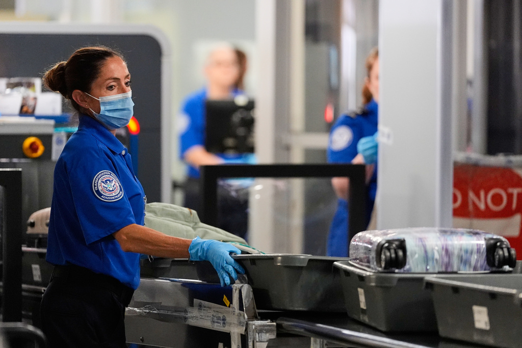 TSA agent pushes bins along at a security checkpoint at the Dallas Fort Worth International Airport