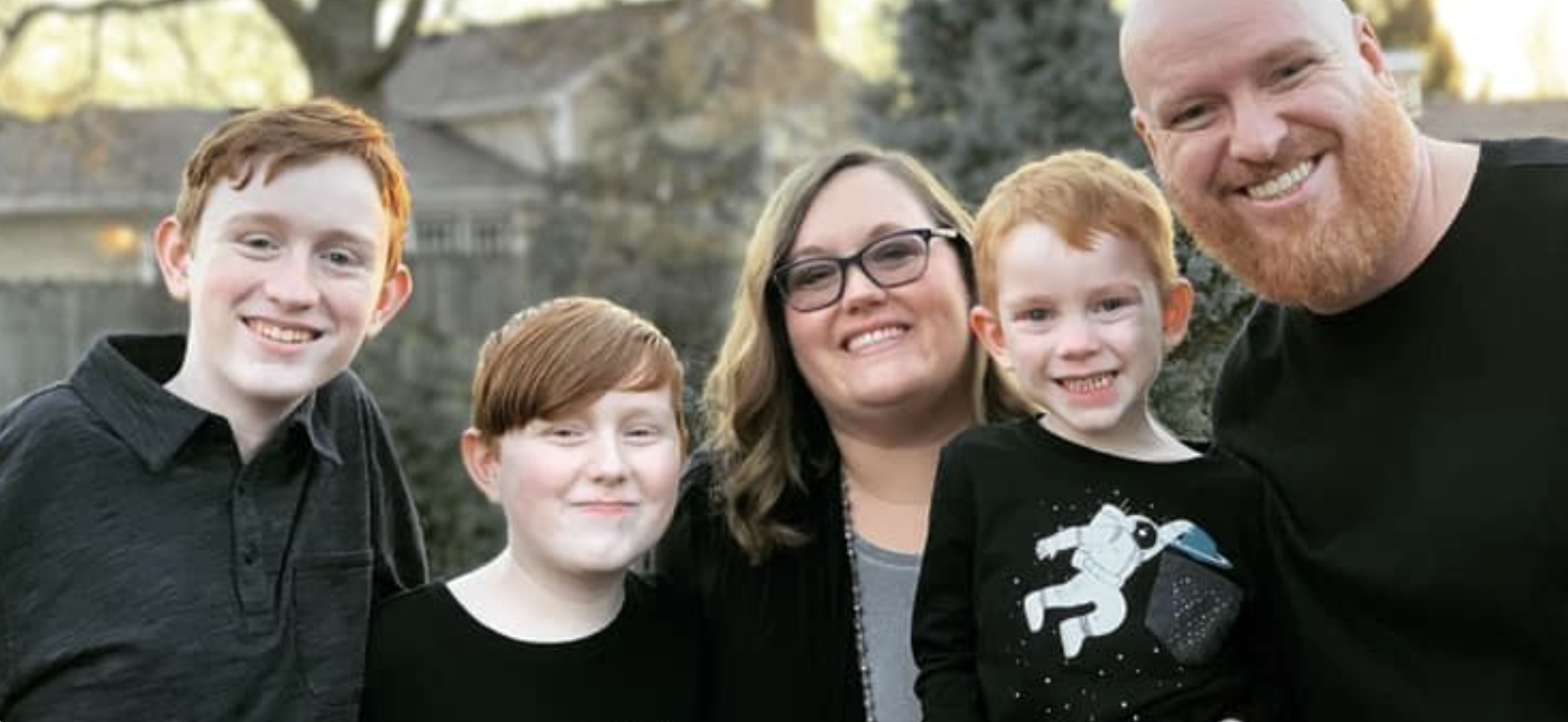 Three smiling children and a smiling wife and husband