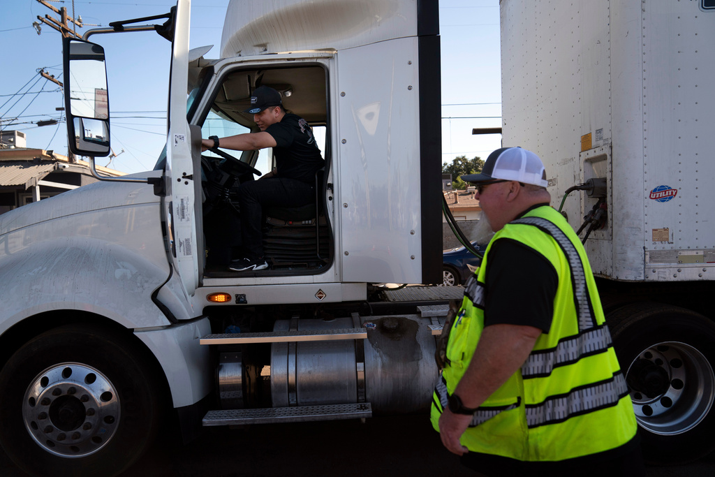 A student driver gets on a truck as the instructor watches
